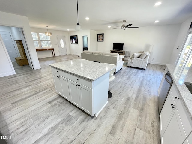 kitchen featuring recessed lighting, pendant lighting, ceiling fan with notable chandelier, light wood-style flooring, and light stone counters
