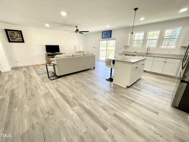 kitchen with open floor plan, white cabinets, a breakfast bar, and light wood-style floors