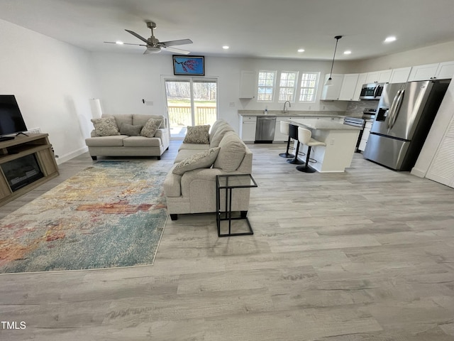 living room with recessed lighting, light wood-style flooring, baseboards, and a ceiling fan