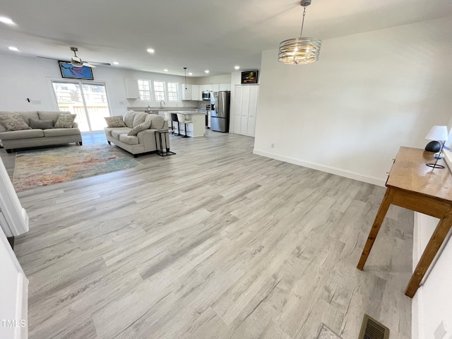 living area featuring visible vents, light wood-style flooring, recessed lighting, and baseboards