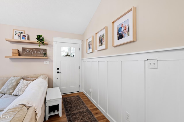 entryway featuring vaulted ceiling, wood finished floors, and a wainscoted wall