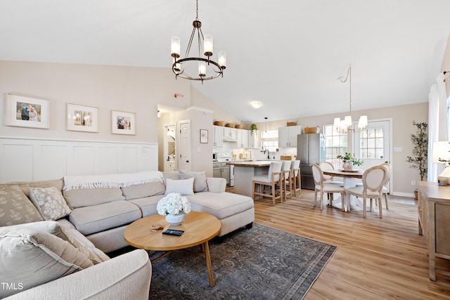 living area with an inviting chandelier, light wood-type flooring, and high vaulted ceiling