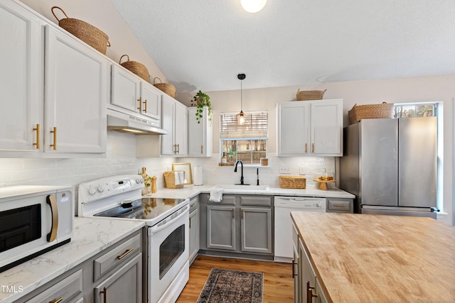 kitchen with white appliances, butcher block countertops, under cabinet range hood, and gray cabinetry