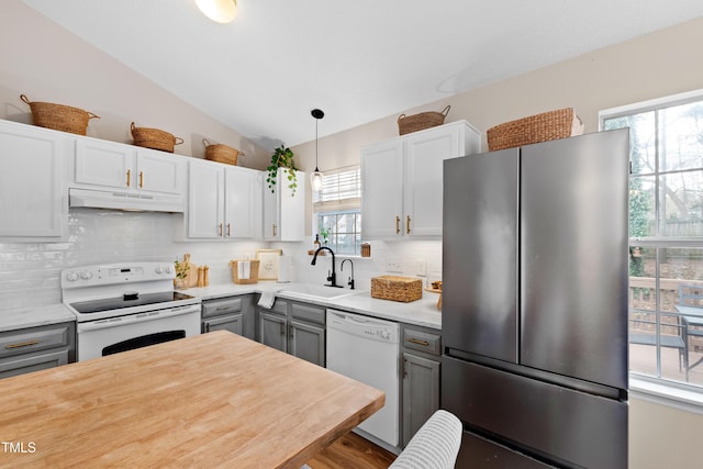 kitchen featuring gray cabinetry, under cabinet range hood, light countertops, white appliances, and a sink