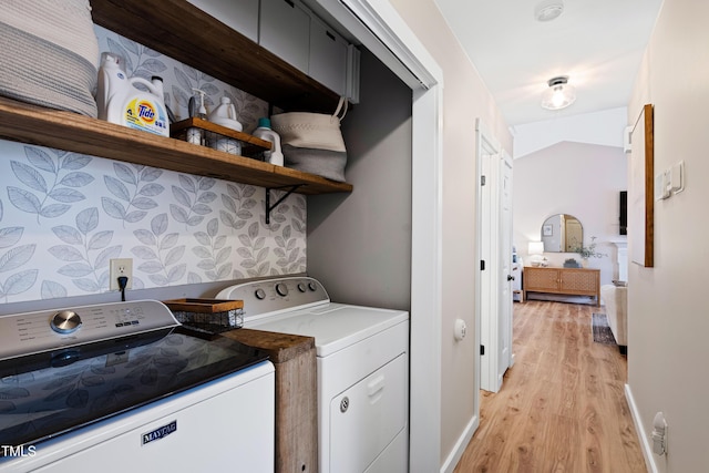 washroom featuring laundry area, baseboards, light wood-type flooring, and washing machine and clothes dryer