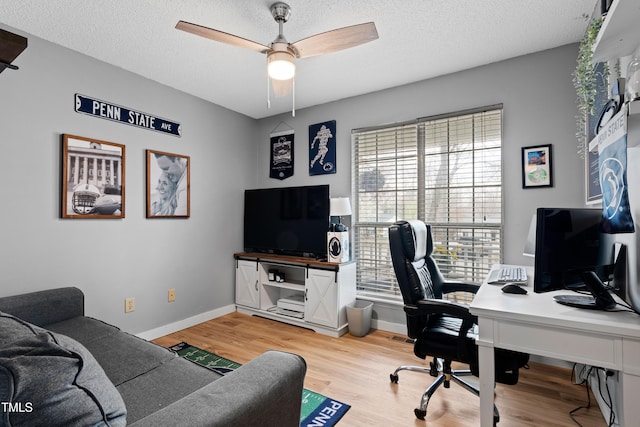 office space with baseboards, a textured ceiling, a ceiling fan, and light wood finished floors