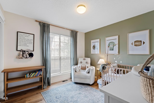 bedroom with visible vents, a textured ceiling, and light wood-style flooring