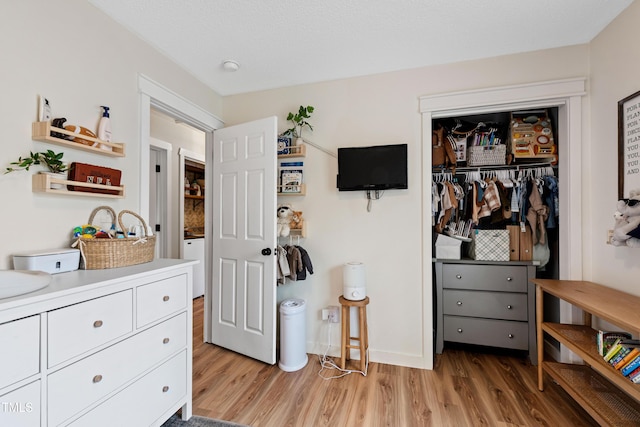 bedroom featuring a closet, light wood-type flooring, baseboards, and a sink