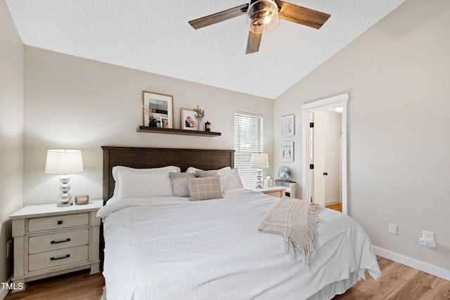 bedroom featuring vaulted ceiling, a ceiling fan, baseboards, and light wood finished floors