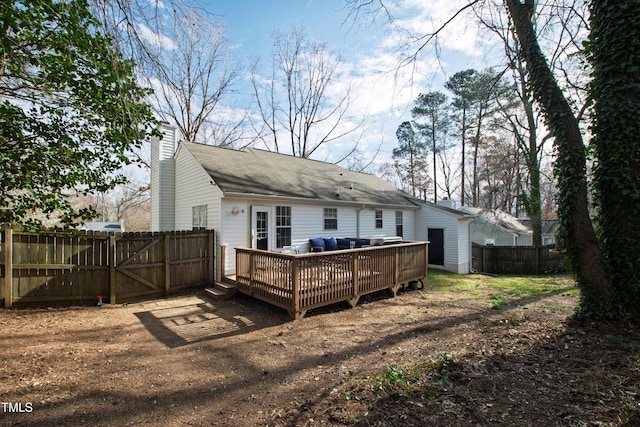 rear view of house with a gate, fence, a chimney, and a wooden deck