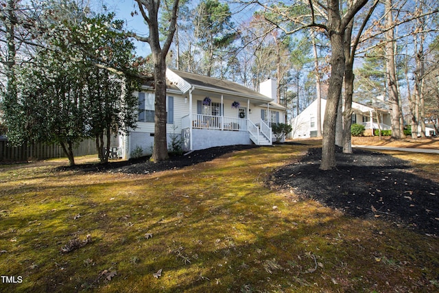 view of front of house featuring a front yard, covered porch, and a chimney