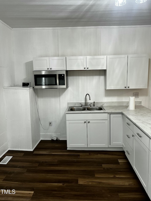 kitchen featuring visible vents, dark wood-type flooring, a sink, stainless steel microwave, and white cabinets