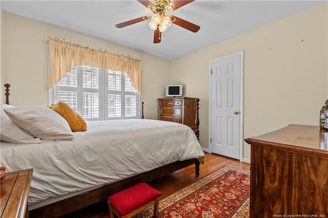 bedroom featuring ceiling fan, baseboards, and wood finished floors