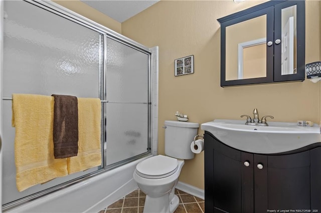 bathroom with toilet, combined bath / shower with glass door, tile patterned flooring, baseboards, and vanity