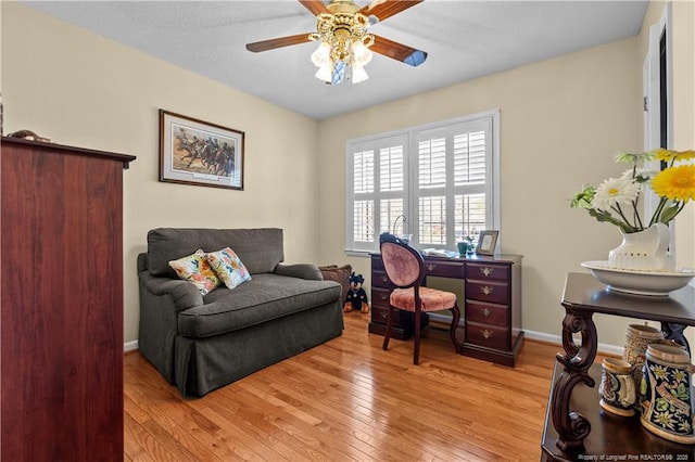 office space featuring baseboards, ceiling fan, and light wood finished floors