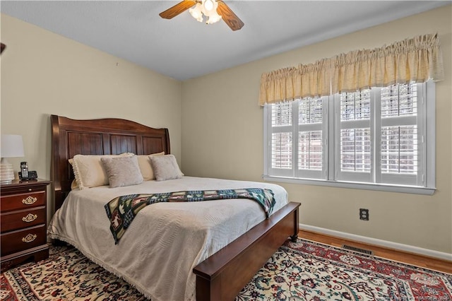 bedroom featuring visible vents, ceiling fan, baseboards, and wood finished floors