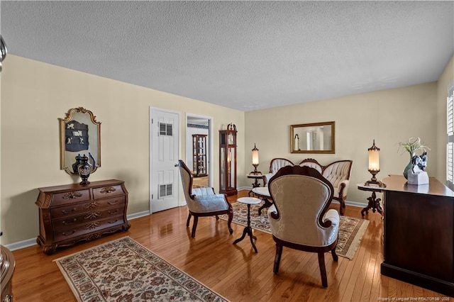 sitting room with a textured ceiling, baseboards, and wood finished floors