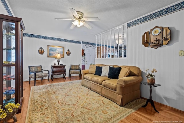 living area with a textured ceiling, a ceiling fan, and wood finished floors