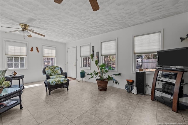 living area featuring light tile patterned floors, a ceiling fan, and a textured ceiling