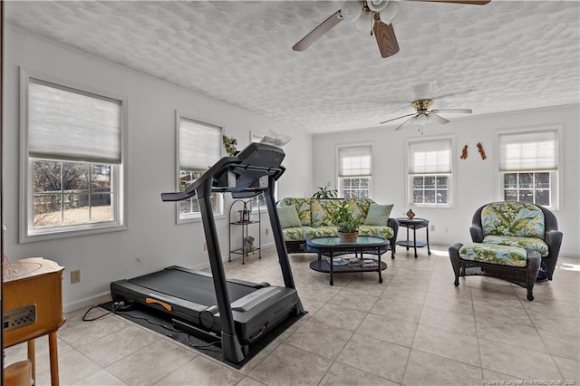 exercise area with light tile patterned floors, baseboards, and a textured ceiling