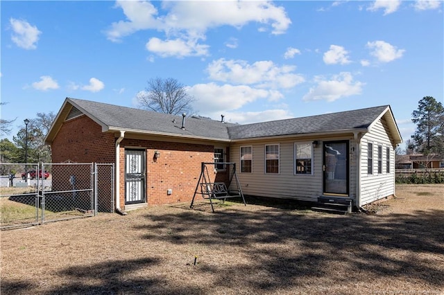 rear view of house featuring entry steps, a gate, fence, and brick siding