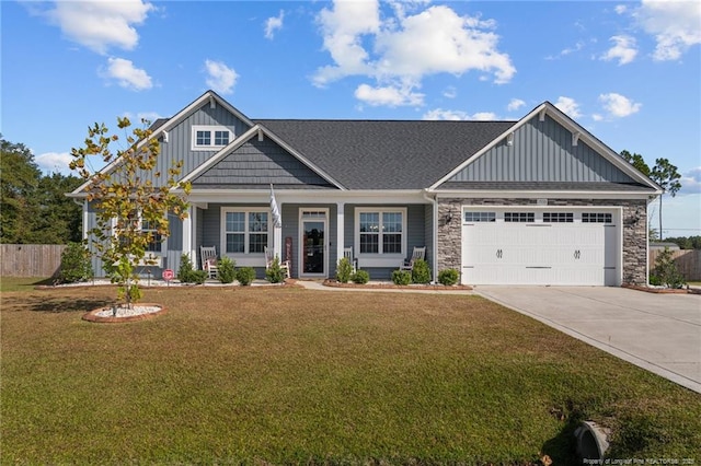 craftsman-style home with board and batten siding, concrete driveway, a front yard, stone siding, and an attached garage