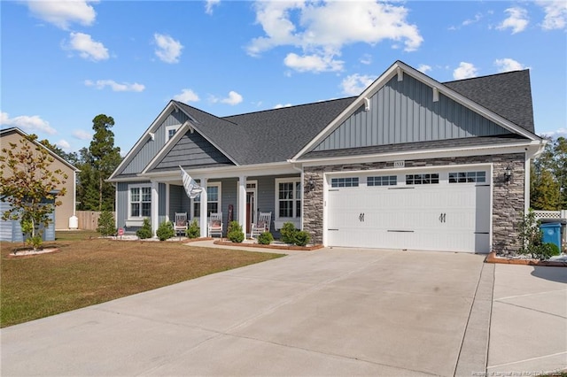 craftsman-style house featuring a front yard, an attached garage, covered porch, concrete driveway, and board and batten siding