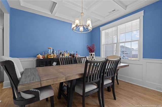 dining area featuring an inviting chandelier, light wood-style floors, coffered ceiling, and beam ceiling