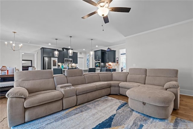 living area with baseboards, ornamental molding, recessed lighting, ceiling fan with notable chandelier, and wood finished floors