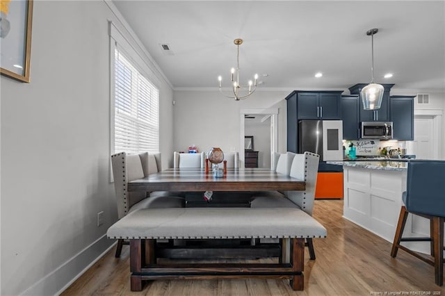 dining room featuring visible vents, baseboards, crown molding, and light wood finished floors