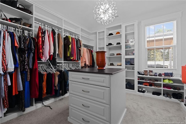 walk in closet featuring a chandelier and carpet floors