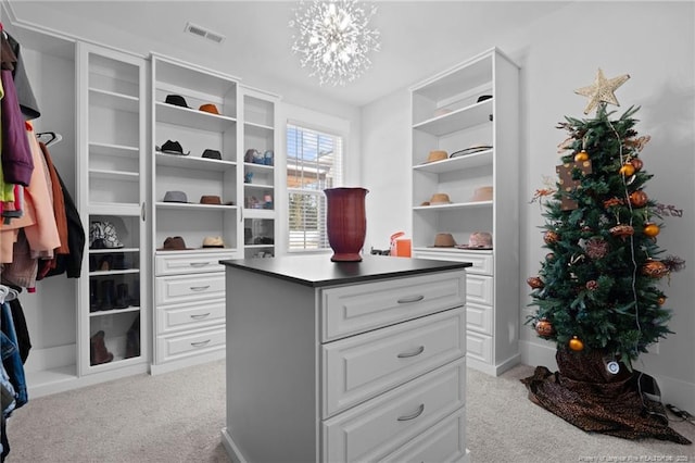 walk in closet featuring visible vents, an inviting chandelier, and carpet floors