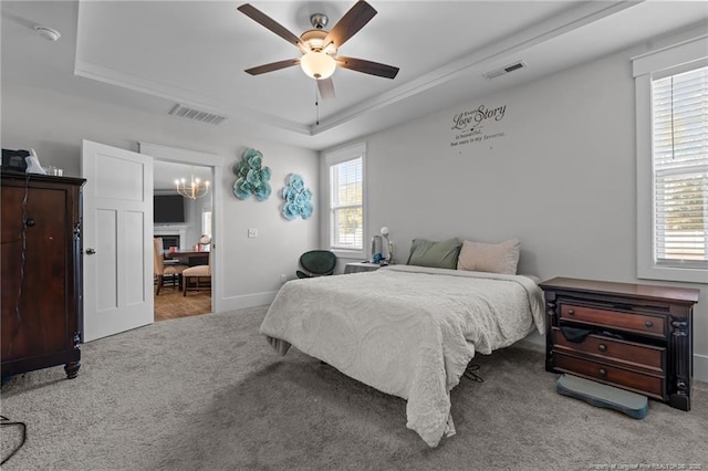 bedroom with a tray ceiling, multiple windows, and visible vents