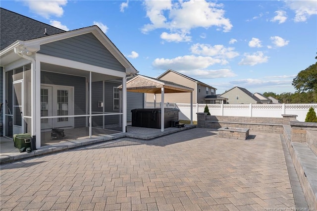 view of patio with a sunroom, a fenced backyard, and a hot tub