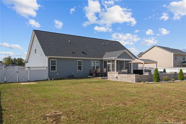 back of property with a yard, a sunroom, a fenced backyard, and a gate