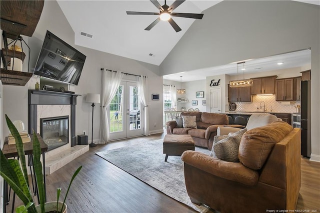 living room featuring visible vents, baseboards, a premium fireplace, french doors, and wood finished floors