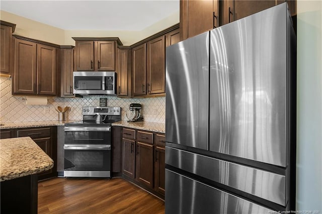 kitchen with decorative backsplash, dark wood-style floors, light stone countertops, and stainless steel appliances