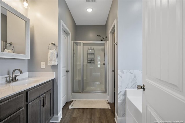 bathroom with visible vents, a garden tub, a stall shower, wood finished floors, and vanity