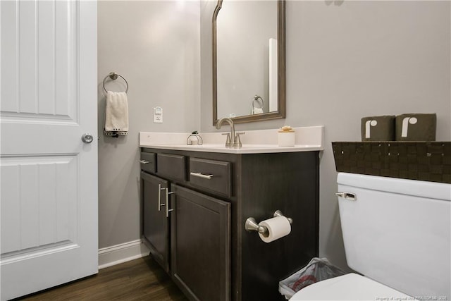 bathroom featuring baseboards, toilet, wood finished floors, and vanity