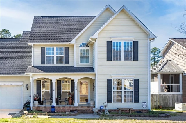 traditional-style home featuring a porch, a shingled roof, and a garage