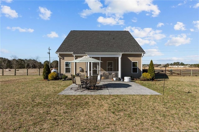 back of house featuring a lawn, a shingled roof, a patio, and fence