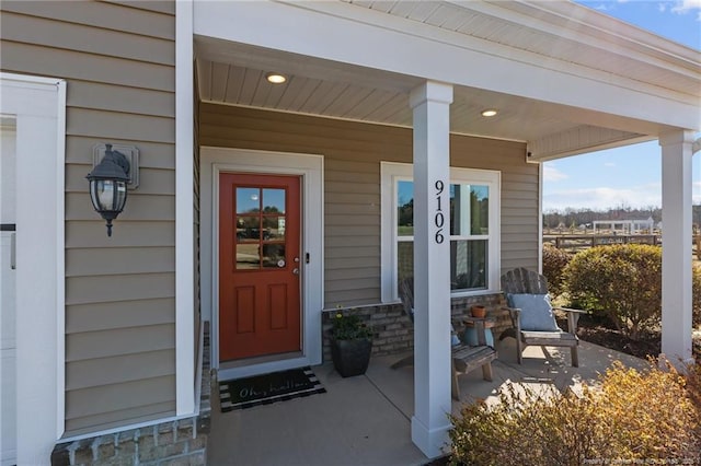 doorway to property with covered porch and stone siding