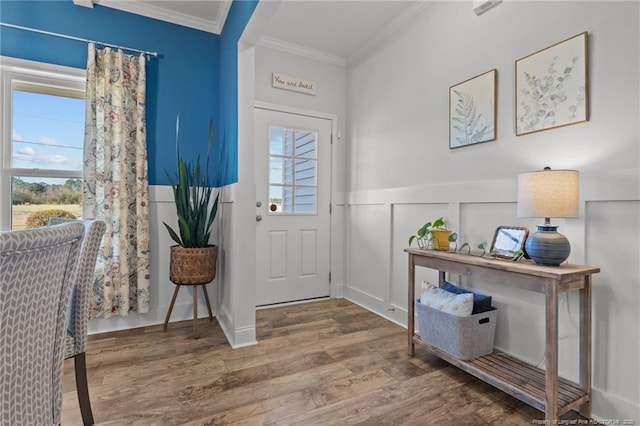 entrance foyer featuring a decorative wall, a wainscoted wall, crown molding, and wood finished floors