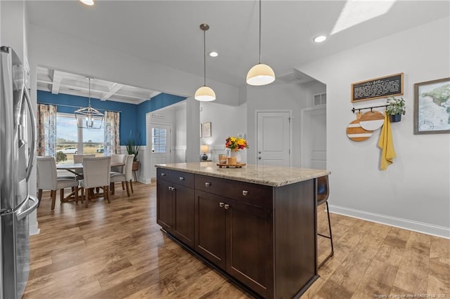 kitchen featuring dark brown cabinetry, beamed ceiling, freestanding refrigerator, wood finished floors, and coffered ceiling