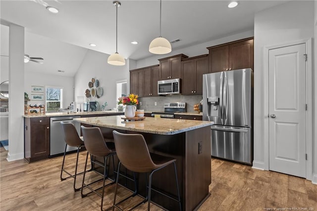 kitchen featuring dark brown cabinets, appliances with stainless steel finishes, a center island, and light wood-style floors