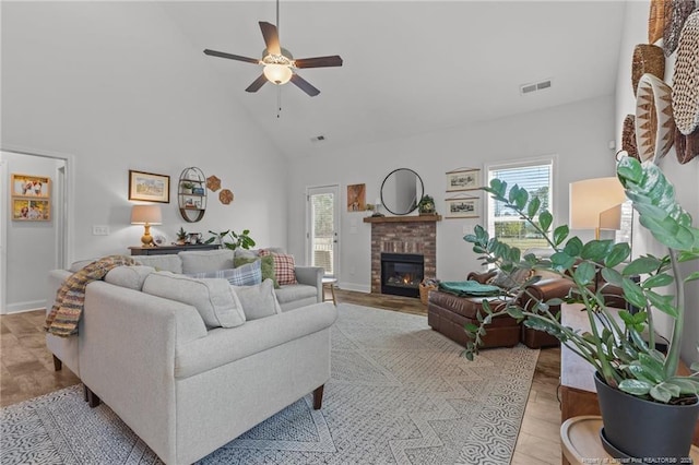 living room with plenty of natural light, a brick fireplace, high vaulted ceiling, and visible vents