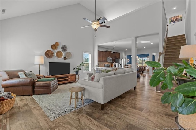 living area with visible vents, high vaulted ceiling, stairs, and wood finished floors