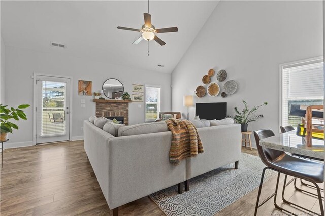 living area with wood finished floors, a fireplace, visible vents, and a healthy amount of sunlight