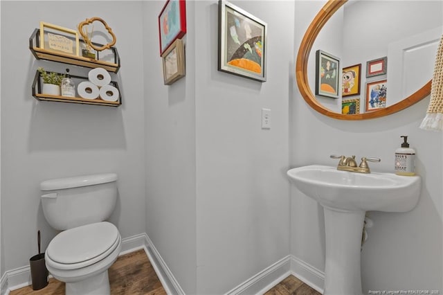 bathroom with toilet, baseboards, and wood finished floors