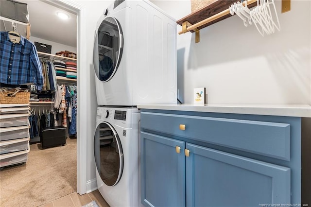 laundry area with cabinet space, light colored carpet, and stacked washing maching and dryer